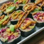 A savory vegan sushi bake with layers of rice, tofu, avocado, and nori, topped with spicy mayo.